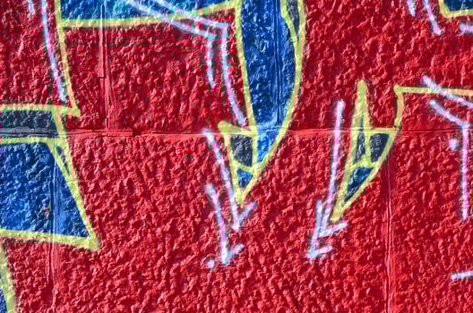 Fragment of graffiti drawings. The old wall decorated with paint stains in the style of street art culture. Colored background texture in warm tones photo