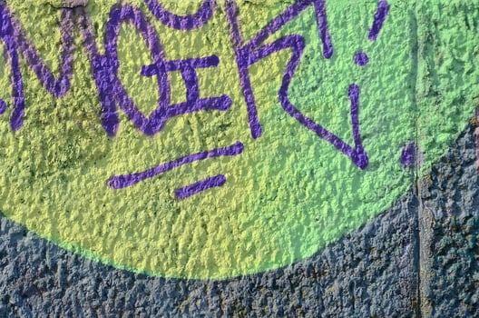 Fragment of graffiti drawings. The old wall decorated with paint stains in the style of street art culture. Colored background texture in warm tones photo