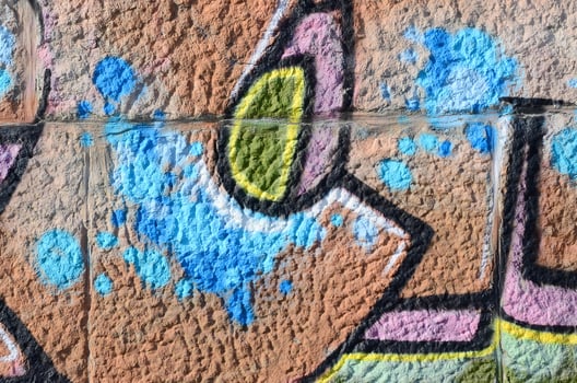 Fragment of graffiti drawings. The old wall decorated with paint stains in the style of street art culture. Colored background texture in warm tones photo