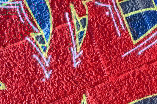 Fragment of graffiti drawings. The old wall decorated with paint stains in the style of street art culture. Colored background texture in warm tones photo