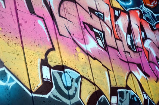 A fragment of detailed graffiti of a drawing made with aerosol paints on a wall of concrete tiles. Background image of street art in beige and pink color tones photo