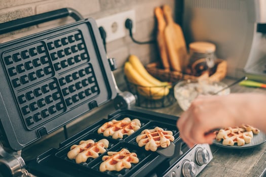 Young woman preparing Belgian waffles in the kitchen. Cooking process photo
