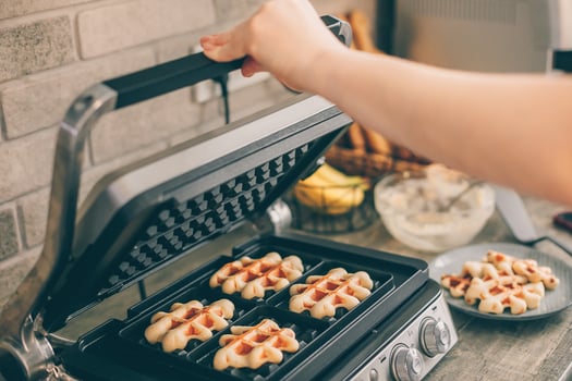 Young woman preparing Belgian waffles in the kitchen. Cooking process photo