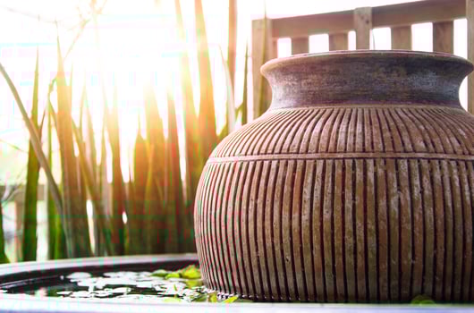 The evening sun shines on the water basin where the jar is placed inside. photo