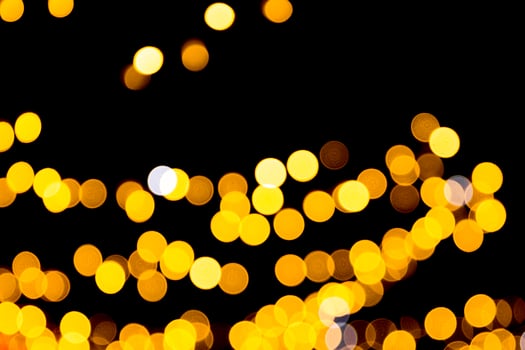 Defocused city gold night bokeh abstract background. blurred many round yellow light on dark background photo