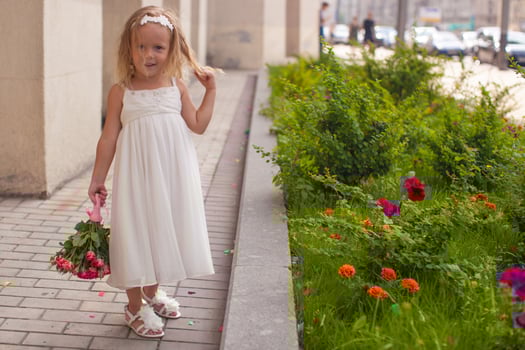 Beautiful little girl with bouquet of roses in her hand at the wedding photo