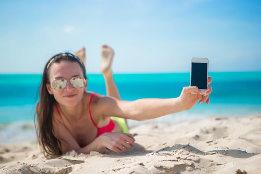 Young woman with her cell phone on white beach photo