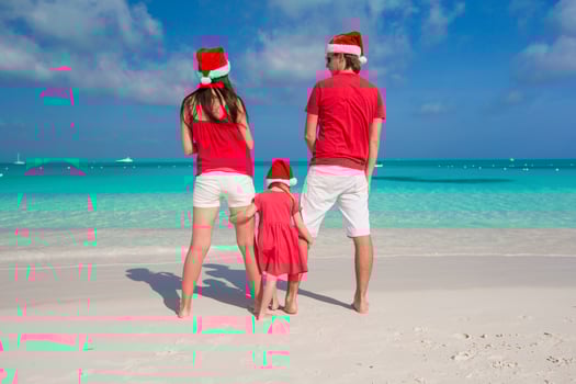 Happy family in Christmas Hats having fun on white beach photo