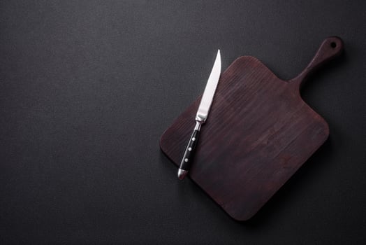 Empty brown wooden cutting board on dark concrete background photo