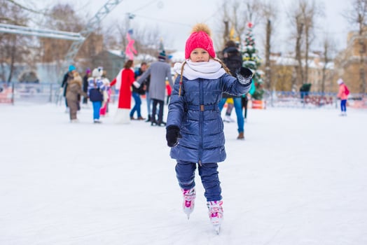 Cute little girl skating on the ice rink outdoors photo