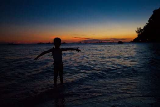 Silhouette of little girl at sunset on the island Boracay, Philippines photo
