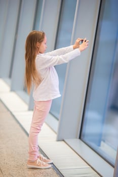 Little girl in airport near big window while wait for boarding photo