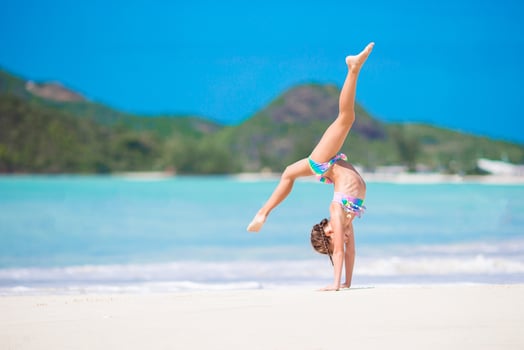 Active little girl at beach having a lot of fun. Sporty kid making the wheel on the seashore photo