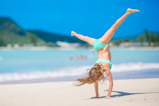 Adorable active little girl at beach during summer vacation photo