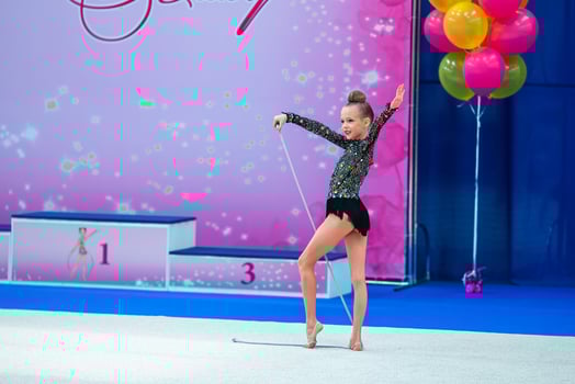 Beautiful little gymnast girl on the carpet on the competition photo
