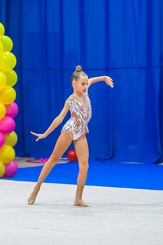 Beautiful little gymnast girl on the carpet on the competition photo