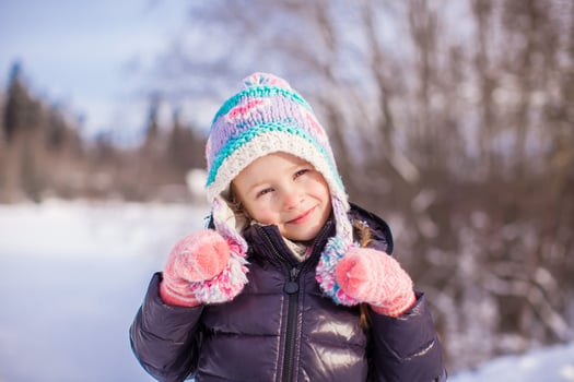 Portrait of little adorable girl in winter hat at snowy forest photo