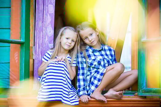 Adorable little girls in the window of rural house outdoors photo