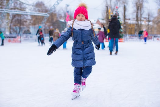 Adorable little girl skating on the ice-rink photo