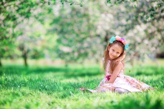 Adorable little girl in blooming cherry tree garden on spring day photo