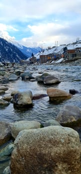 A river with rocks and snow covered mountains in the background photo
