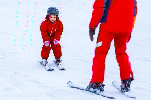 Professional ski instructor is teaching a child to ski on a sunny day on a mountain slope resort with sun and snow. Family and children active vacation. photo