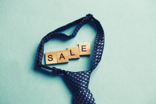 the word sale made by wooden cubes on a blue background with a tie. photo