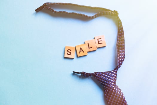 the word sale made by wooden cubes on a blue background with a tie. photo