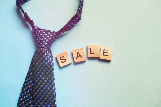 the word sale made by wooden cubes on a blue background with a tie. photo