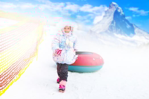 Little girl with snowtube ready for sledding down a hill photo