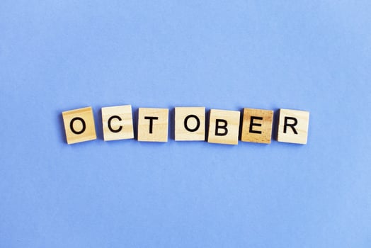 inscription October made by wooden cubes on a veri peri purple background. photo