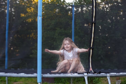 Little child girl jumping on the trampoline in the back yard photo