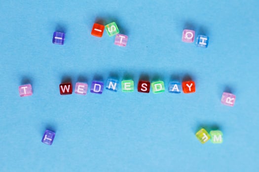 inscription wednesday made by multicolor plastic cubes on a blue background. photo
