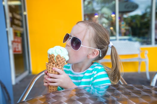 Little girl eating ice cream in a cafe outdoor photo