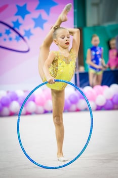 Little gymnast participates in competitions in rhythmic gymnastics photo