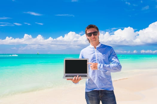 Young man with laptop during beach vacation photo