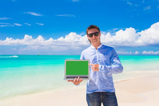 Young man with laptop during beach vacation photo