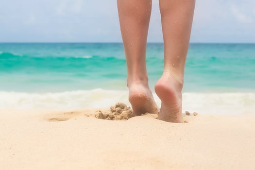 Women's beautiful smooth legs on white sand beach photo