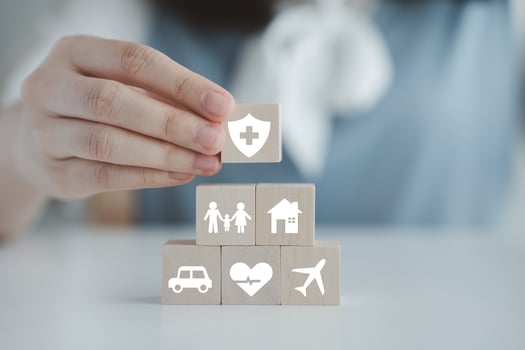 Insurance concept. Protection against a possible eventuality. Hand holding security symbol and house, car, family, travel and health care on wooden block. Life assurance concept. photo