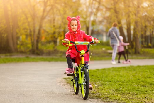 Beautiful smiling little girl riding bicycle in a park photo
