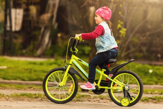 Beautiful smiling little girl riding bicycle in a park photo