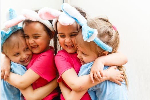 Two smiling girls with rabbit ears holding a box with easter eggs on background. photo