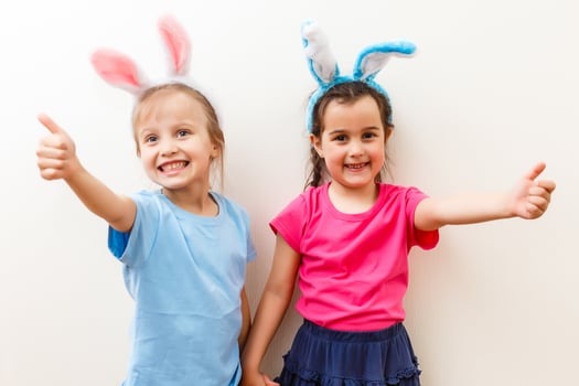 Two smiling girls with rabbit ears holding a box with easter eggs on background. photo