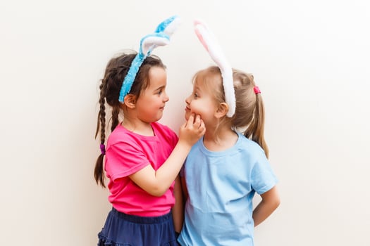 Two smiling girls with rabbit ears holding a box with easter eggs on background. photo