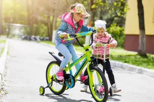 two kids on scooter and bike in the park, family sport photo