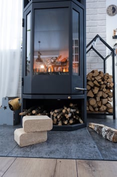 Fuel briquettes made of pressed sawdust for kindling the furnace - economical alternative eco-friendly fuel for the fireplace in the house. Firewood is burning in the oven in the interior photo