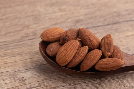 Salted almonds in wooden spoon on wooden background photo