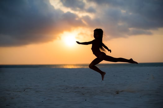 Silhouette of adorable little girl on white beach at sunset photo