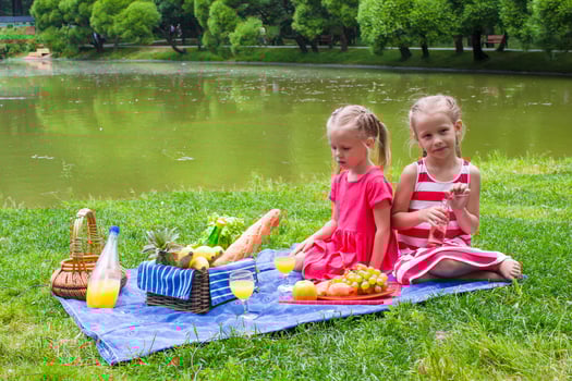 Adorable little girls picnicing in the park at sunny day photo