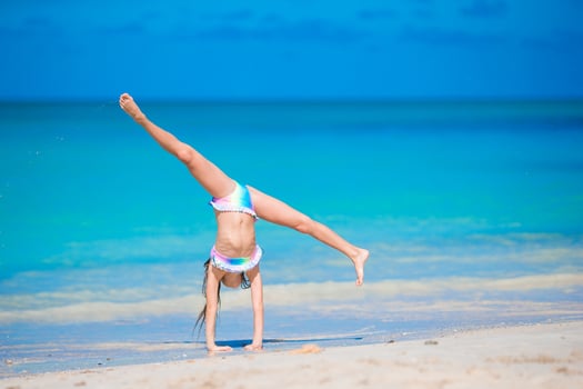 Adorable active little girl at beach during summer vacation photo